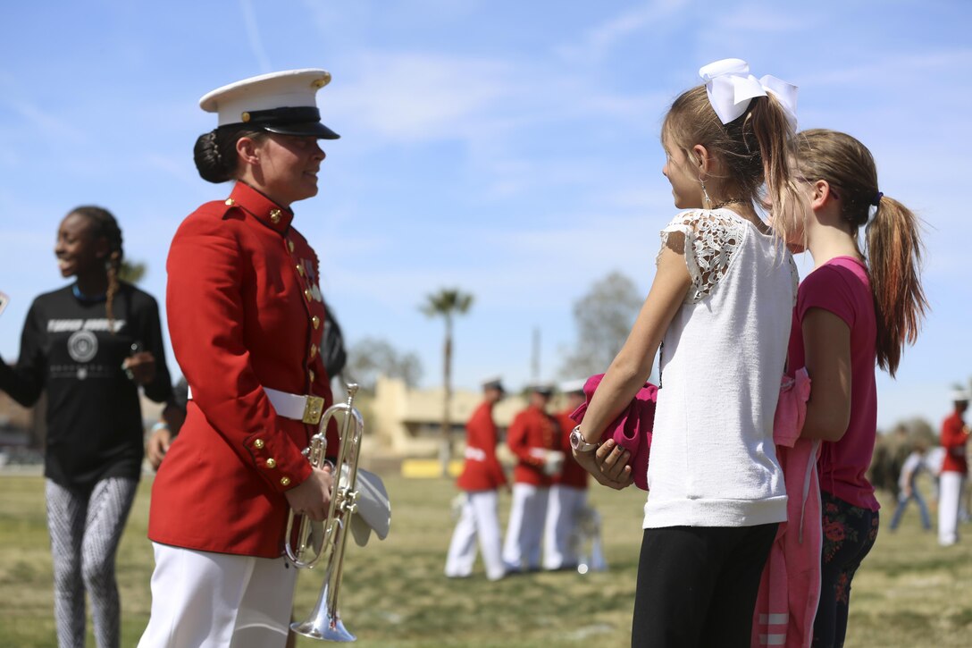 Cpl. Megan Almojuela, a member of the , U.S. Marine Corps Drum & Bugle Corps, interacts with two young fans after the Battle Color Ceremony at Lance Cpl. Torrey L. Gray Field aboard Marine Corps Air Ground Combat Center, Twentynine Palms, Calif., March 8, 2017. The United States Marine Corps Battle Color Detachment travels worldwide annually to demonstrate the discipline and “Esprit de Corps” of United States Marines. (U.S. Marine Corps photo by Lance Cpl. Natalia Cuevas)