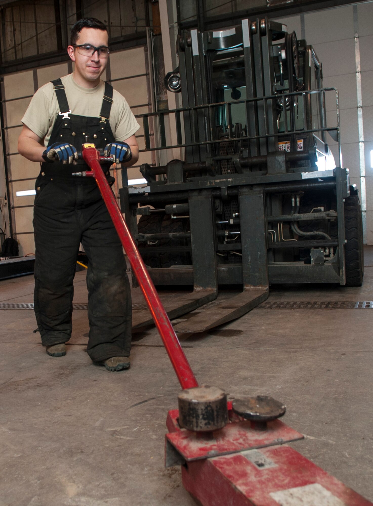 Airman Steven Velasquez, 5th Logistics Readiness Squadron vehicle maintenance technician, pushes an air-actuated jack at Minot Air Force Base, N.D., Feb. 28, 2017. Tire shop maintainers use this tool to both raise and lower vehicles when replacing damaged tires. (U.S. Air Force photo/Airman 1st Class Jonathan McElderry)