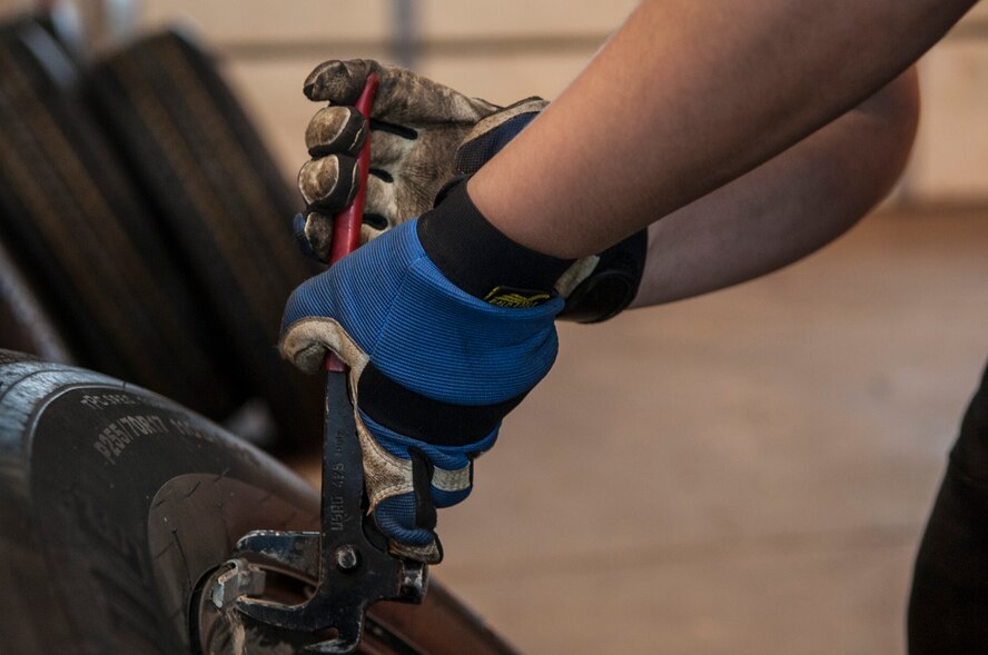 An Airman with the 5th Logistics Readiness Squadron tire shop removes weights from a tire at Minot Air Force Base, N.D., Feb. 28, 2017. Maintainers put weights on each tire to provide proper air distribution, which ensures the government vehicle tires remain serviceable. (U.S. Air Force photo/Airman 1st Class Jonathan McElderry)