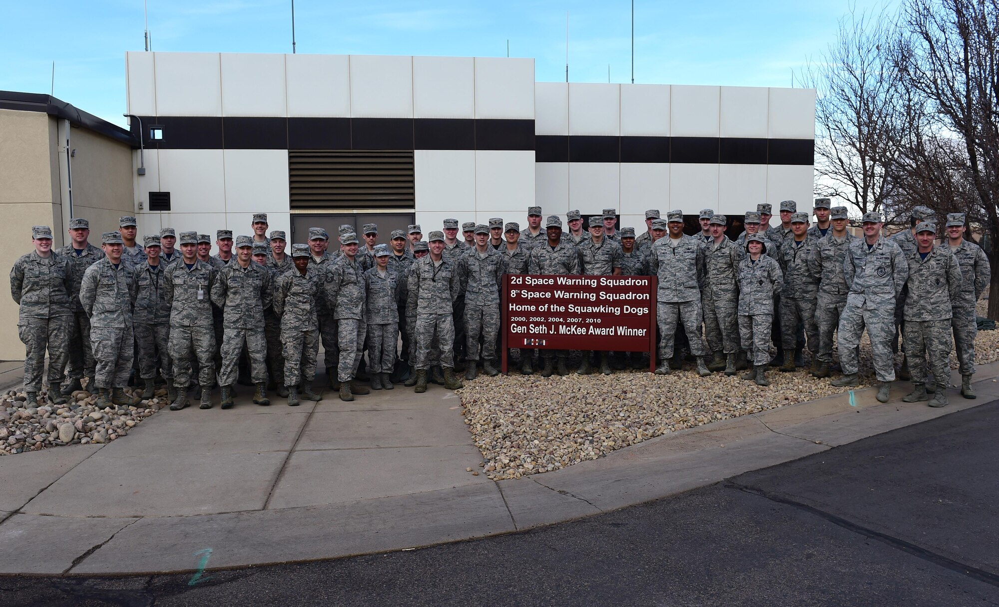 Members of the 2nd Space Warning Squadron pose for a photo March 10, 2017, around the Gen. Seth J. McKee award sign on Buckley Air Force Base, Colo. The McKee award was presented to the 2nd SWS for being recognized as the best missile warning squadron of 2016 in the Air Force Space Command. The “2016” is yet to be installed on the sign. (U.S. Air Force photo by Airman Jacob Deatherage/Released)