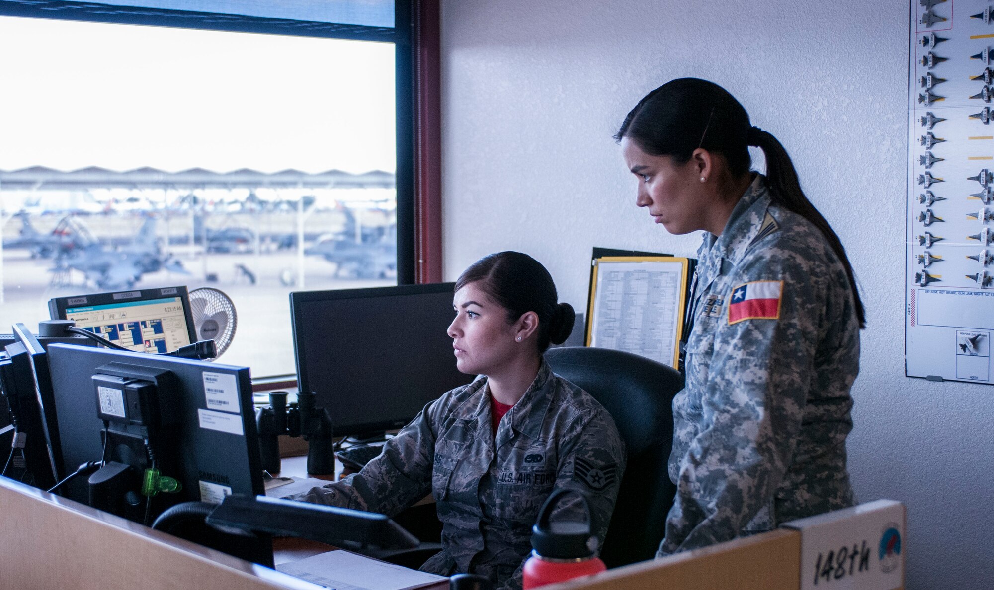 Capt. Andrea Garcia, right, a Chilean air force exchange officer, monitors maintenance operations on the 162nd Wing flight line from the wing’s maintenance operations center with Staff Sgt. Emma Yslas.  (U.S. Air National Guard photo by Staff Sgt. Gregory Ferreira)