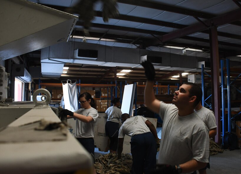 U.S. Airmen throw unserviceable uniforms into a shredder at Al Udeid Air Base, Qatar, March 10, 2017. As an operational security measure, unserviceable uniform items are shredded to prevent them from being obtained by adversaries. (U.S. Air Force photo by Senior Airman Miles Wilson)