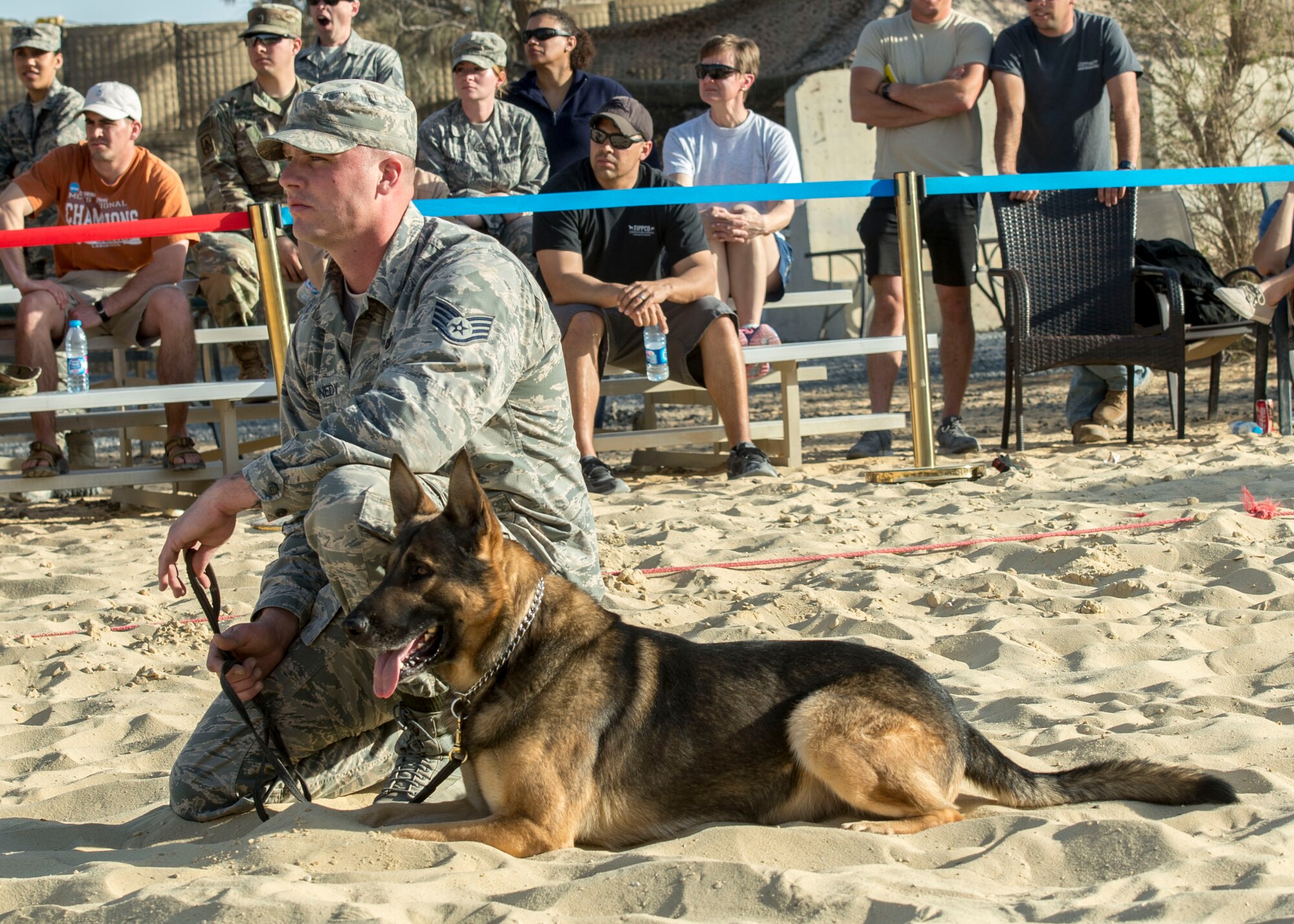 Staff Sgt. Jeffrie Kennedy, 332nd Expeditionary Security Forces Squadron military working dog handler, kneels with his dog Nico, during a demonstration, Feb. 25, 2017, in Southwest Asia. The demonstration showcased several techniques that included following commands, guarding a suspect, and attacking. (U.S. Air Force photo by Staff Sgt. Eboni Reams)