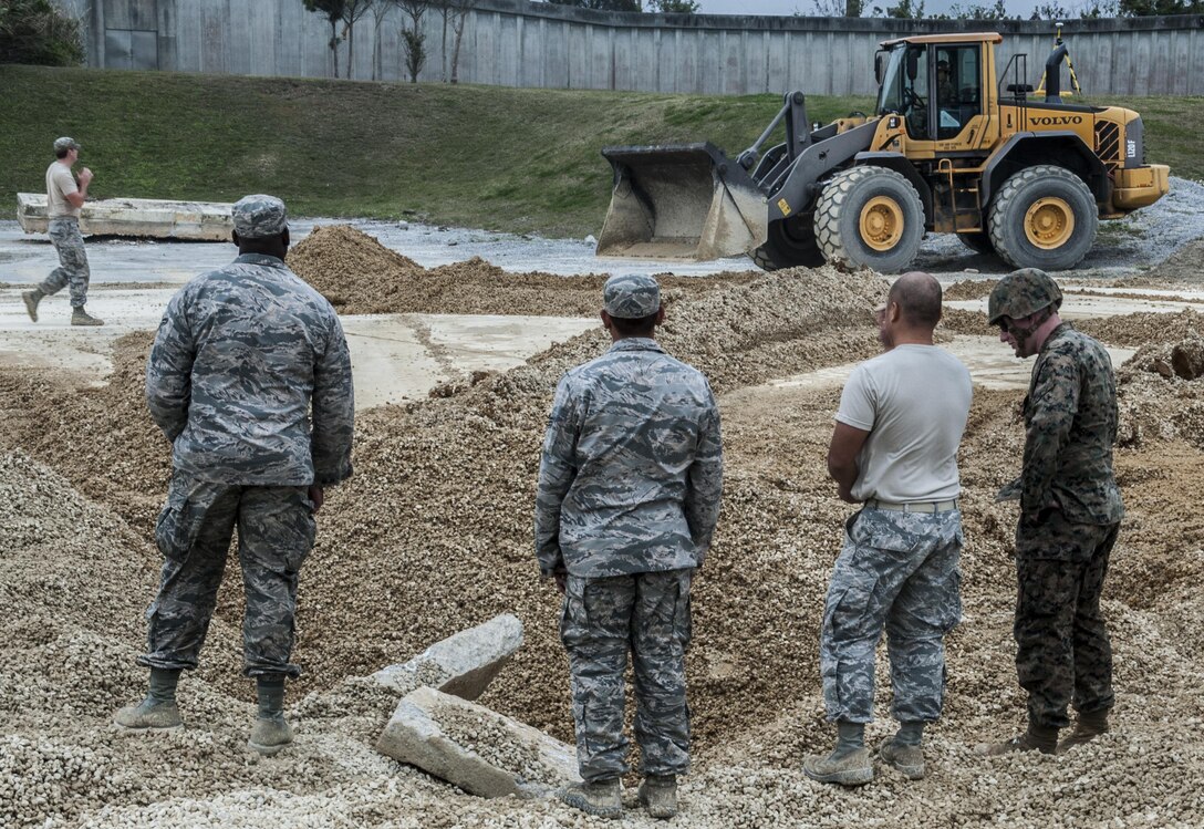 U.S. Air Force Staff Sgt. Chue Her, Airman Brandon Mclendon and Senior Airman Justin Hewitt, 18th Civil Engineer Group pavement maintenance and heavy equipment operator demonstrate procedures for airfield damage repair at the munitions storage area of Kadena Air Base, Japan, March 3, 2017. The exercise took place March 2-3, allowing members of the Air Force, Navy and Marine Corps to demonstrate their capabilities. (U.S. Air Force photo by Senior Airman Nick Emerick/Released) 