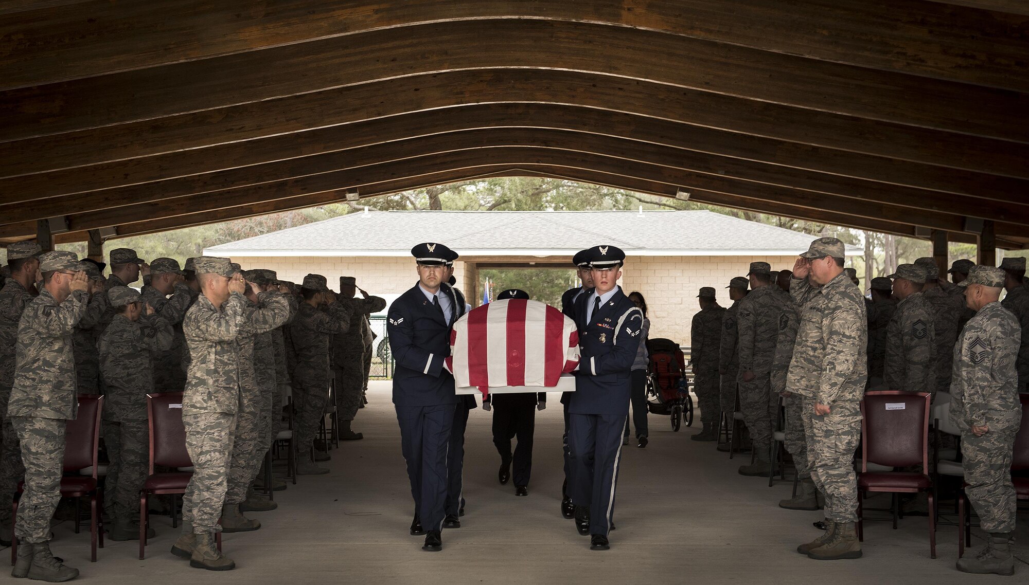 People in attendance salute as the casket, carried by Eglin Honor Guard, passes by during the unit’s graduation ceremony at Eglin Air Force Base, Fla., March 1.  Approximately 12 new Airmen graduated from the 120-plus-hour course. The graduation performance includes flag detail, rifle volley, pall bearers and bugler for friends, family and unit commanders. (U.S. Air Force photo/Samuel King Jr.)