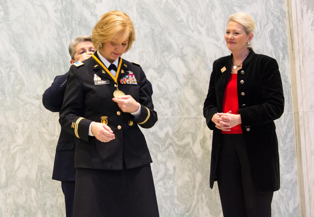 Retired Command Sgt. Maj. Cindy Pritchett places a medal around Chief Warrant Officer 5 Phyllis Wilson’s neck, while retired Brig. Gen. Anne MacDonald looks on, as Wilson is inducted at the U.S. Army Women’s Foundation Hall of Fame Induction ceremony in Washington, D.C., on March 8, 2017.  MacDonald is the president of the USAWF.