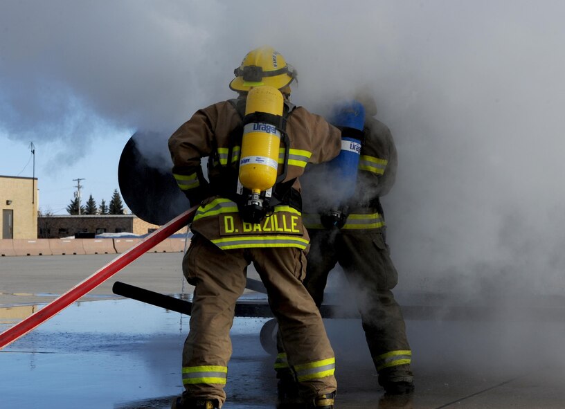 Dustin Bazille, Kenmore fire department firefighter, and Tim McCartney North Lemmon fire department firefighter, put out a simulated fire at Minot Air Force Base, N.D., Feb. 24, 2017. Bazille and McCartney trained with the Minot AFB fire department, which included several training events with a final simulated helicopter fire on the flight line. (U.S. Air Force photo/Staff Sgt. Chad Trujillo)