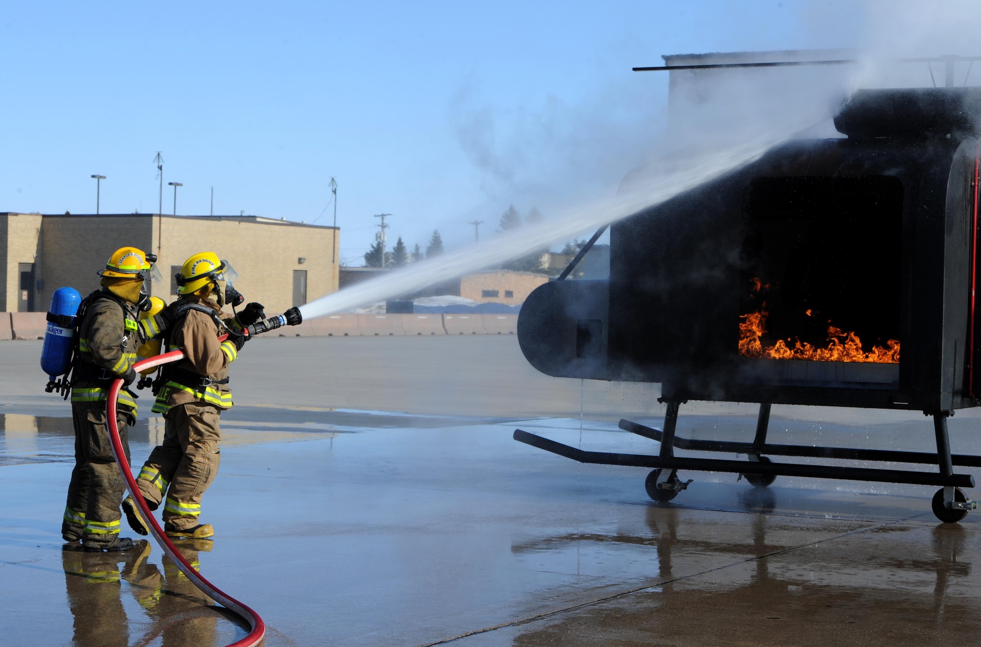 Dustin Bazille, Kenmore fire department firefighter, and Tim McCartney North Lemmon fire department firefighter, put out a simulated fire at Minot Air Force Base, N.D., Feb. 24, 2017. The Minot AFB fire department hosted training with local fire departments, scenarios included simulated helicopter fire and missile field response. (U.S. Air Force photo/Staff Sgt. Chad Trujillo)