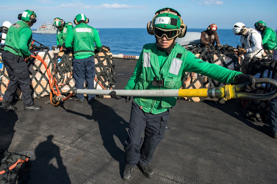 Navy Petty Officer 2nd Class Brian Do carries a cargo hook during a vertical replenishment on the flight deck of the aircraft carrier USS Carl Vinson in the South China Sea, March 5, 2017. Navy photo by Petty Officer 2nd Class Sean M. Castellan