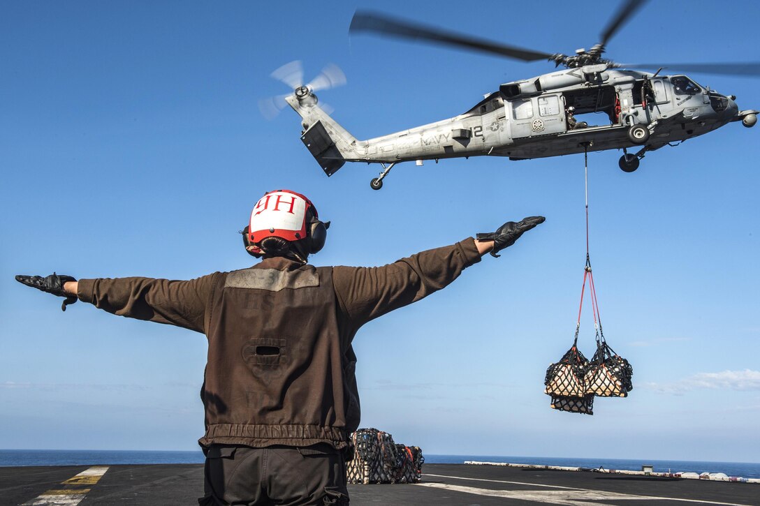 Navy Seaman Rebecca Geissinger directs the crew of an MH-60S Sea Hawk helicopter during a vertical replenishment aboard the aircraft carrier USS Carl Vinson in the South China Sea, March 5, 2017. Geissinger is an aviation ordnanceman airman. The helicopter crew is assigned to Helicopter Sea Combat Squadron 4. Navy photo by Petty Officer 2nd Class Sean M. Castellan