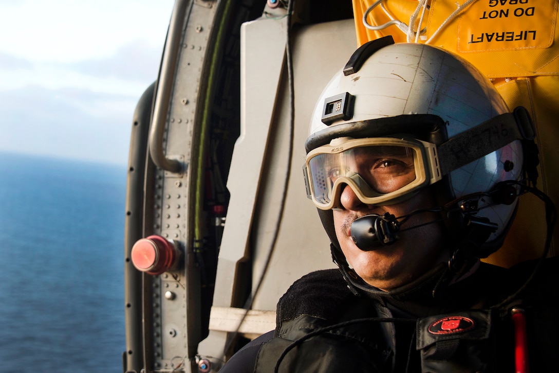 Navy Petty Officer 1st Class Hermilo Perez flies in an MH-60S Sea Hawk helicopter above the aircraft carrier USS Carl Vinson in the South China Sea, March 6, 2017. Perez is a helicopter naval aircrewman assigned to Helicopter Sea Combat Squadron 4. Navy photo by Petty Officer 3rd Class Devin M. Monroe
