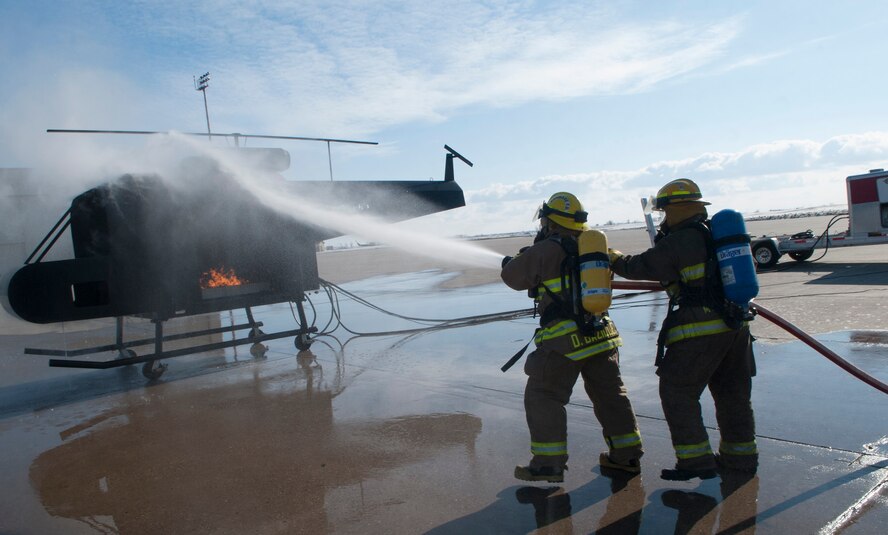 (From left) Dustin Bazille, Kenmare Fire Department firefighter, and Tim McCartney, North Lemmon Fire Department firefighter, spray water onto a mobile trainer at Minot Air Force Base, N.D., Feb. 24, 2017. The 5th Civil Engineer fire department invited several local fire departments for missile field response training. (U.S. Air Force photo/Airman 1st Class Jonathan McElderry)