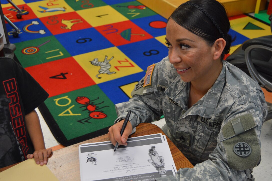 U.S. Army Reserve Staff Sgt. Claudia Martinez with the 4th Sustainment Command (Expeditionary) hands out Read Across America certificates to students at Kinder Ranch Elementary in San Antonio, TX, Mar. 10, 2017. 