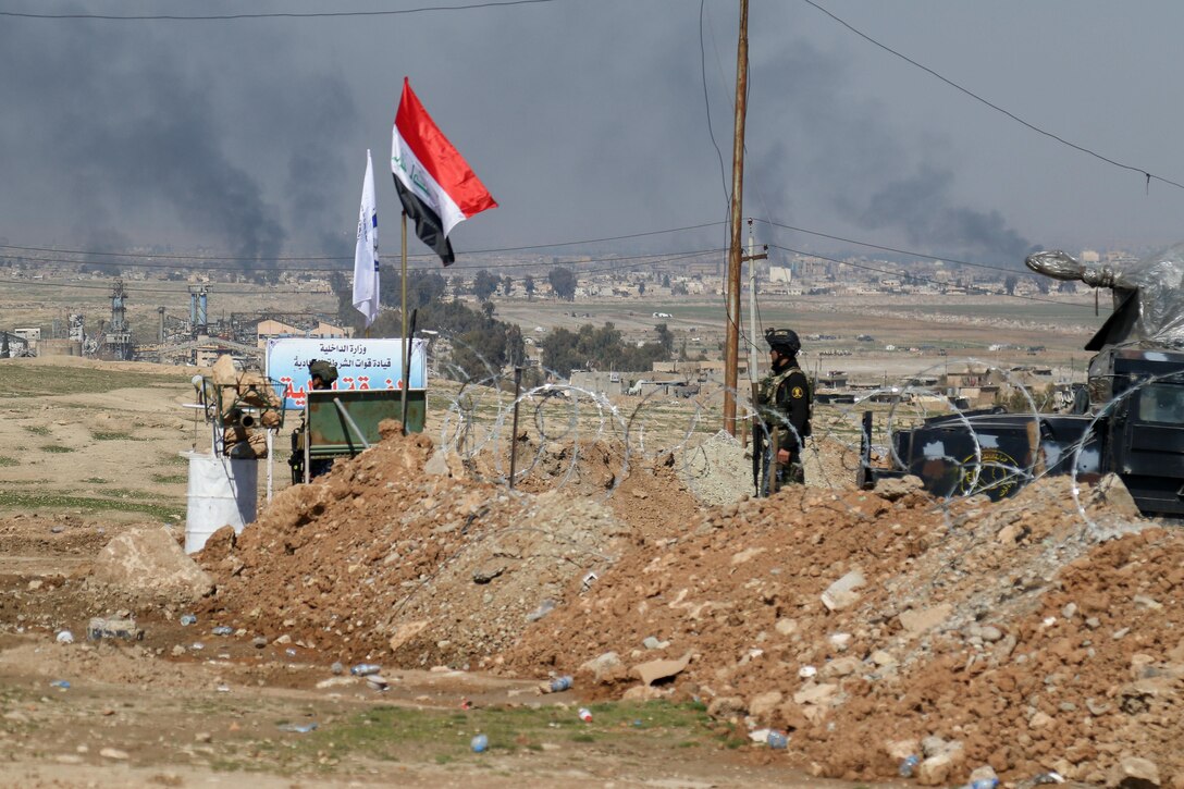 Iraqi federal police members, supported by Combined Joint Task Force-Operation Inherent Resolve, guard Abu Saif, Iraq, as the battle to liberate West Mosul rages in the background, March 6, 2017. CJTF-OIR is the global Coalition to defeat ISIS in Iraq and Syria. (U.S. Army photo by Staff Sgt. Jason Hull)