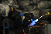 Senior Airman Tate Lawson, 5th Civil Engineer heating, ventilation, air conditioning and refrigeration technician, solders valves onto a compressor at Minot Air Force Base, N.D., Feb. 28, 2017. These technicians install, diagnose and perform repairs on all HVAC systems on base. (U.S. Air Force photo/Senior Airman Kristoffer Kaubisch)