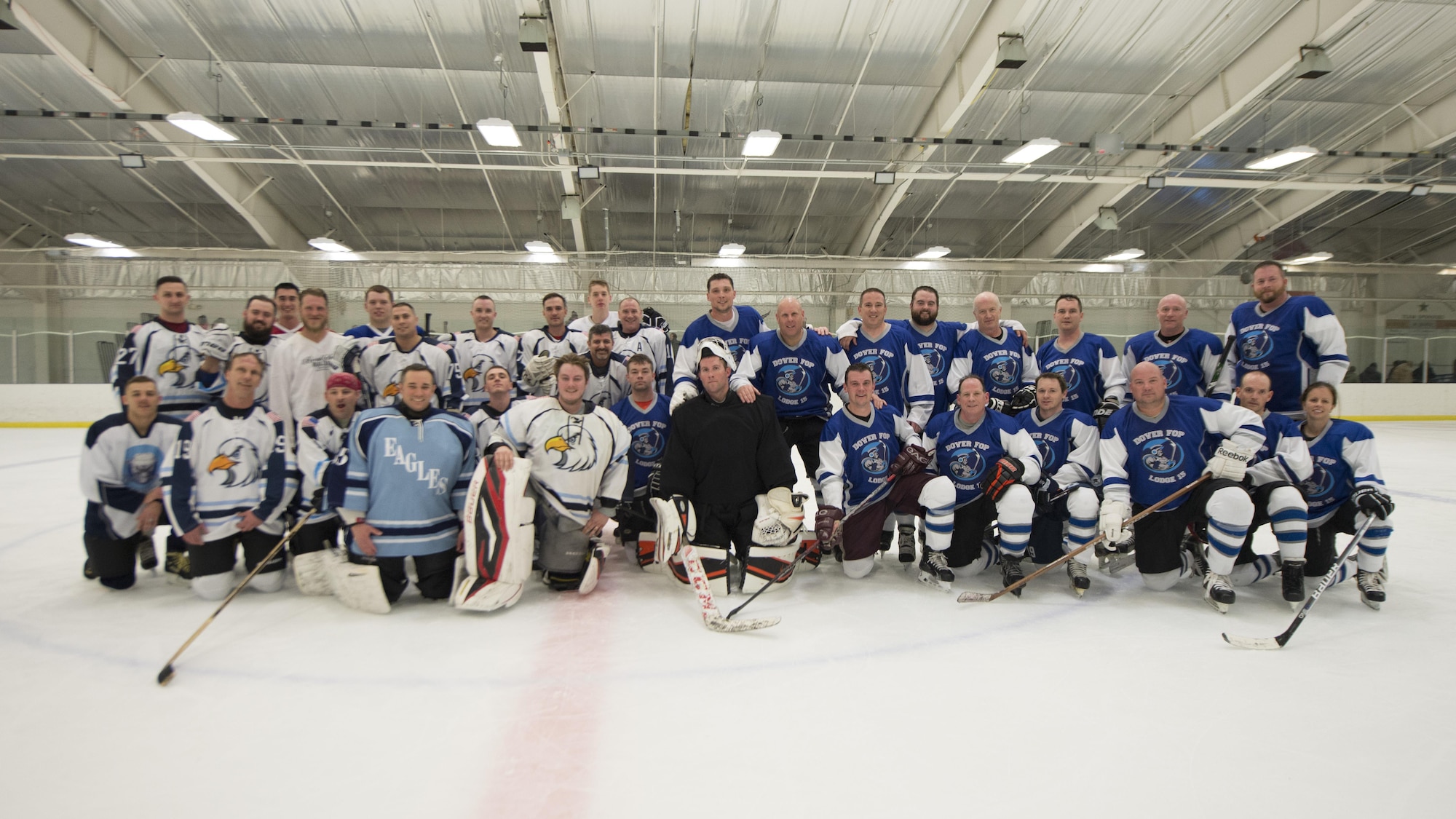 The Dover Eagles and Fraternal Order of Police Lodge 15 hockey teams pose for a group photo after a charity hockey game March 11, 2017, at the Centre Ice Rink in Harrington, Del. The proceeds of the game went to the family of Correctional Officer Lt. Steven Floyd, who was killed in the line of duty. (U.S. Air Force photo by Senior Airman Zachary Cacicia)