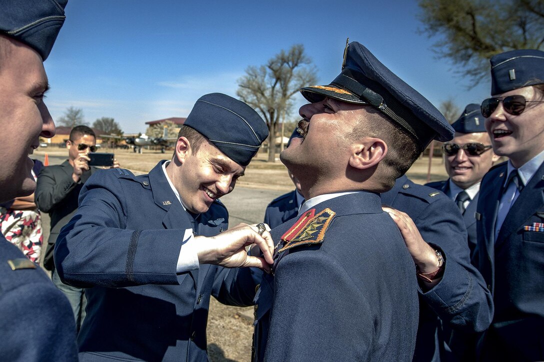 Air Force specialized undergraduate pilot training students gather to fasten pilot wings on an Iraqi air force classmate at Vance Air Force Base, Okla., March 10, 2017, after the class graduation ceremony. Air Force photo by David Poe