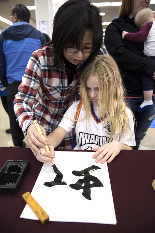 A local Japanese volunteer for the Japanese American Society teaches an American child how to write “Rainbow” in calligraphy during the 60th Annual Culture Festival at Marine Corps Air Station Iwakuni, Japan, March 11, 2017. The festival included Japanese dance performances, decorated exhibits and traditional activities and rituals. JAS continues to bridge the U.S.-Japan friendship by providing quality cultural events and activities. (U.S. Marine Corps photo by Lance Cpl. Carlos Jimenez)