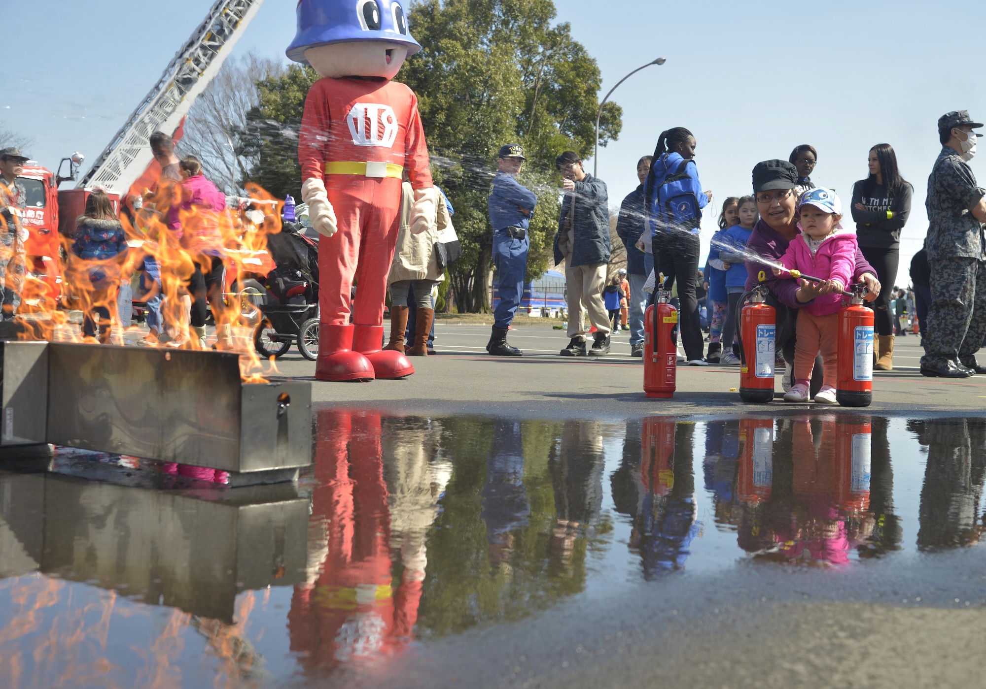 Jessika Carnahan helps her daughter Kathryn put out a simulated fire during the Yokota Safety and Readiness Festival at Yokota Air Base, Japan, March 10, 2017. The festival held an array of demonstrations and booths to encourage base residents and community members to apply risk management in their daily lives and provide information to assist them. (U.S. Air Force photo by Staff Sgt. David Owsianka)