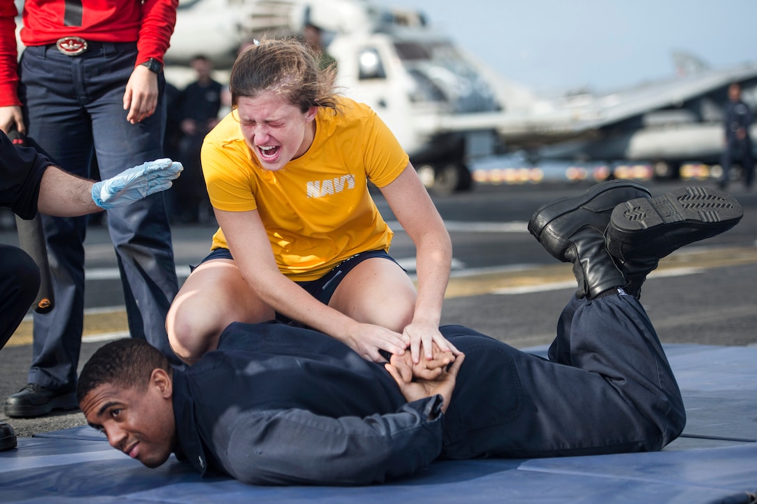 Navy Ensign Jayne Woolard performs a mechanical advantage control hold on Navy Petty Officer 3rd Class Matthew Alexander after being sprayed with oleoresin capsicum spray during naval security force sentry training aboard the amphibious assault ship USS Makin Island at sea, March 4, 2017. The ship is deployed in the U.S. 5th Fleet area of operations in support of maritime security operations designed to reassure allies and partners, and preserve the freedom of navigation and the free flow of commerce in the region. Navy photo by Petty Officer 3rd Class Devin M. Langer