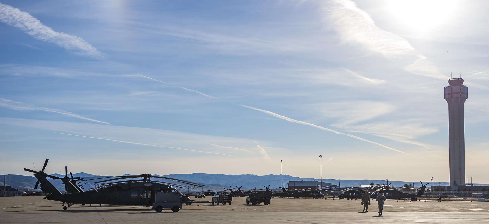 A maintainer and a flight engineer from the 943rd Rescue Group walk on a flightline full of UH-60 Blackhawk and two HH-60G Pave Hawk helicopters, March 2, 2017, at Gowen Field, Idaho, during pre-deployment training for the 305th Rescue Squadron. The 305th RQS, located at Davis-Monthan Air Force Base, Ariz., is conducting training at the Idaho Air National Guard’s Orchard Combat Training Center, a 143,000-acre live-fire range located south of Boise, Idaho, to hone all of their search and rescue procedures before heading to Southwest Asia. (U.S. Air Force photo/Staff Sgt. Jared Trimarchi)