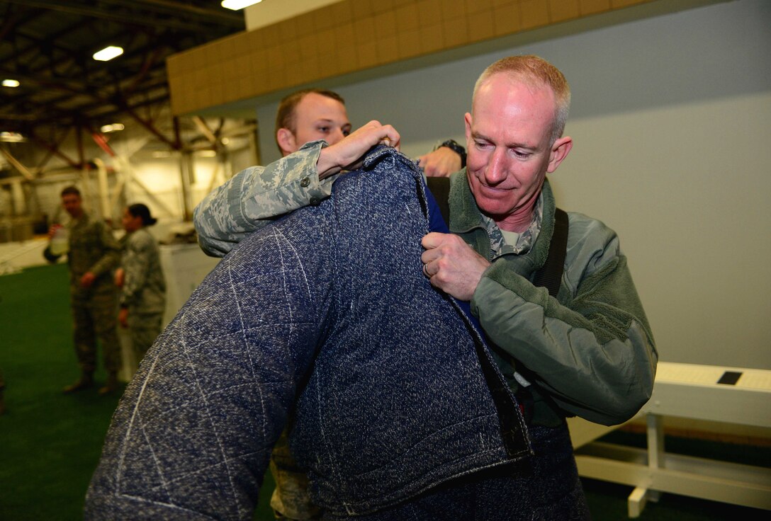 Senior Airman Robert Helvie, a military working dog handler assigned to the 28th Security Forces Squadron, helps Chief Master Sgt. Alan Boling, command chief for the 8th Air Force, into the bite suit during a visit to Ellsworth Air Force Base, S.D., March 9, 2017. MWD handlers train K-9s to detect narcotics or distinct bomb odors to ensure mission effectiveness is not hindered. (U.S. Air Force photo by Airman 1st Class Donald C. Knechtel)