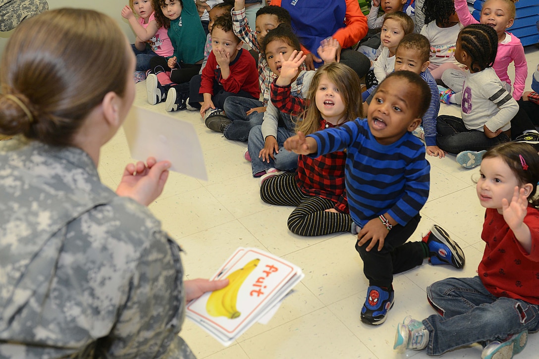 Army Sgt. Nicole Lewis showing cards with healthy foods to children.
