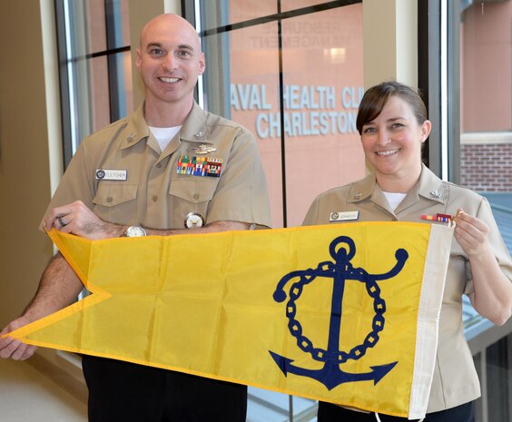 Petty Officer 1st Class Michael Fletcher and Petty Officer 2nd Class Nicole Johnson, hospital corpsmen and command career counselors for Naval Health Clinic Charleston, show off a yellow pennant signifying the Fiscal Year 16
Retention Excellence Award the duo earned recently for NHCC. The pennant will be hoisted to the top of NHCC's flagpole for one year. The award is given to commands that pass the annual Career Information Program Review
with a score of 90 points or better and meet benchmarks showing commitment to the growth and development of Sailors. NHCC passed the CIPR with a score of 100 points, had zero failed-to-submit Career Waypoints applications, and
met or exceeded all aggregate retention benchmarks for enlisted Sailors with 14 years of service or less. 
