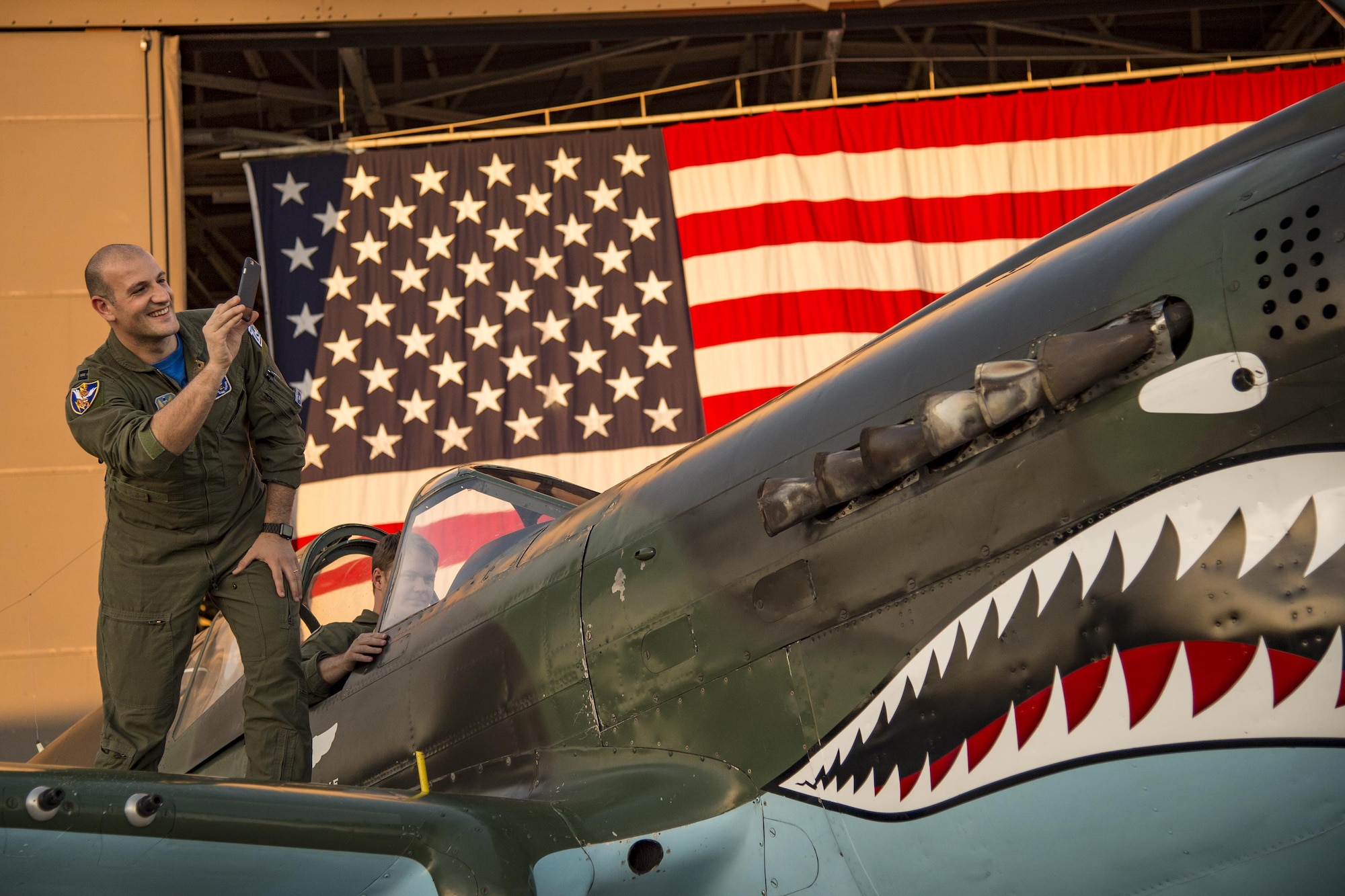 Capt. Roberto Manzo, 74th Fighter Squadron Italian Air Force exchange pilot, takes a photo of the Curtiss P-40 Warhawk static display during the 75th Anniversary Flying Tiger Reunion, March 10, 2017, at Moody Air Force Base, Ga. In 1941, President Roosevelt signed an executive order forming the American Volunteer Group. The AVG was organized into the 1st, 2nd, and 3rd Pursuit Squadrons and later disbanded and replaced by the 23d Fighter Group in 1942. Under the command of Gen. Claire Chennault, the Flying Tigers comprised of the 74th, 75th, and 76th Pursuit Squadrons defended China against the Japanese. Throughout World War II, the Flying Tigers achieved combat success and flew the US-made Curtiss P-40 Warhawks painted with the shark-mouth design. (U.S. Air Force photo by Andrea Jenkins)