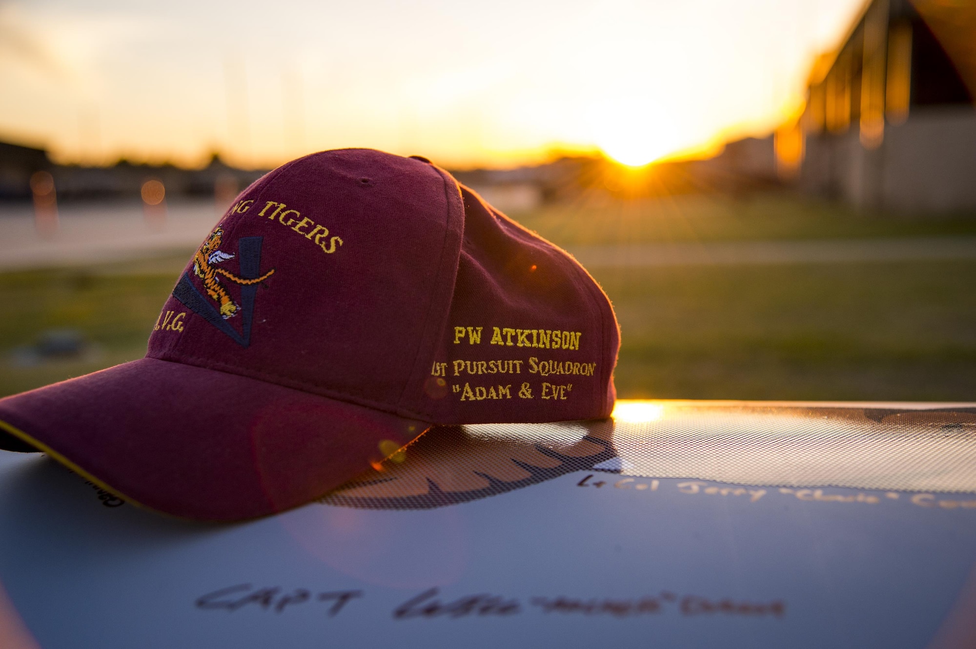 A hat adorned with the name and squadron of a deceased American Volunteer Group member rests on a decorative A-10C Thunderbolt II engine cover during the 75th Anniversary Flying Tiger Reunion, March 10, 2017, at Moody Air Force Base, Ga. In 1941, President Roosevelt signed an executive order forming the American Volunteer Group. The AVG was organized into the 1st, 2nd, and 3rd Pursuit Squadrons and later disbanded and replaced by the 23d Fighter Group in 1942. Under the command of Gen. Claire Chennault, the Flying Tigers comprised of the 74th, 75th, and 76th Pursuit Squadrons defended China against the Japanese. Throughout World War II, the Flying Tigers achieved combat success and flew the US-made Curtiss P-40 Warhawks painted with the shark-mouth design. (U.S. Air Force photo by Andrea Jenkins)