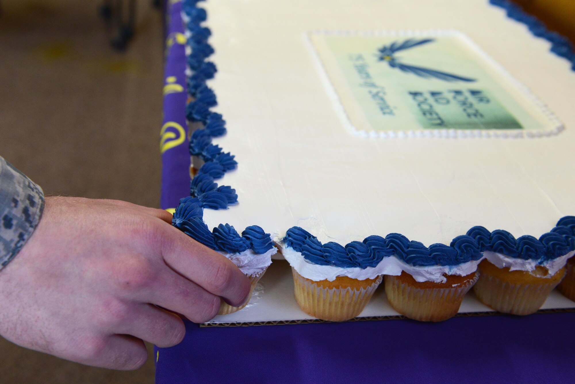 An Airman grabs the first cupcake at the 75th Anniversary of the Air Force Aid Society at the Military and Family Readiness Center at Joint Base Elmendorf-Richardson, Alaska, March 10, 2017. The Air Force Aid Society is the official charity of the U.S. Air Force and fulfills the needs of Airmen and their families through emergency financial assistance, educational support, and community programs since 1942.