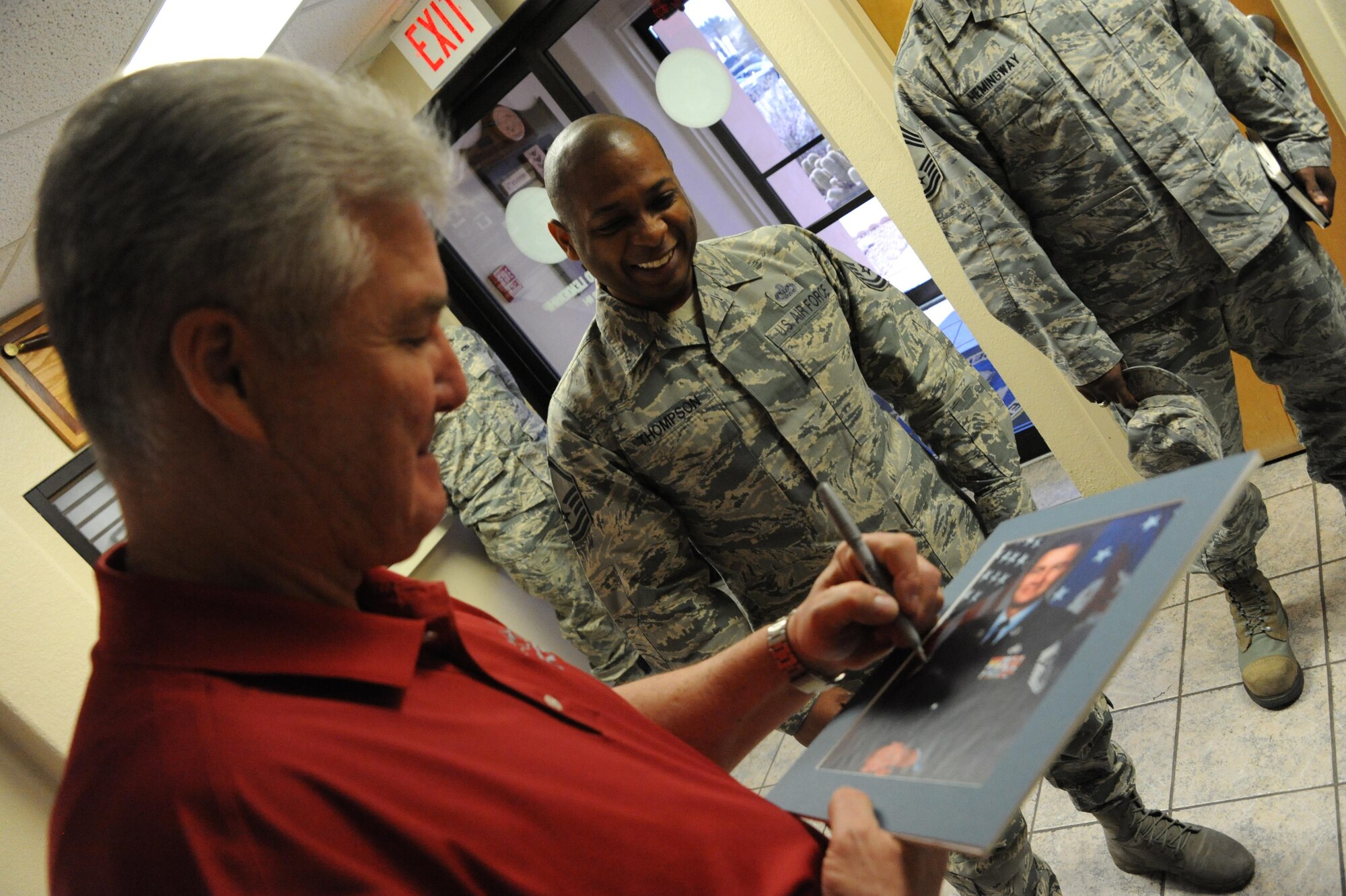 Master Sgt. Bruce Thompson, 56th Force Support Squadron Airmen Leadership School commandant, watches as Retired Chief Master Sgt. of the Air Force Gerald Murray autographs his last official photo from over 10 years ago on March 10, 2017, at Luke Air Force Base, Ariz. Murray visited several different agencies around Luke and was the guest speaker for the Maintenance Professional of the Year event which took place March 11, 2017. (U.S. Air Force photo by Airman 1st Class Caleb Worpel)