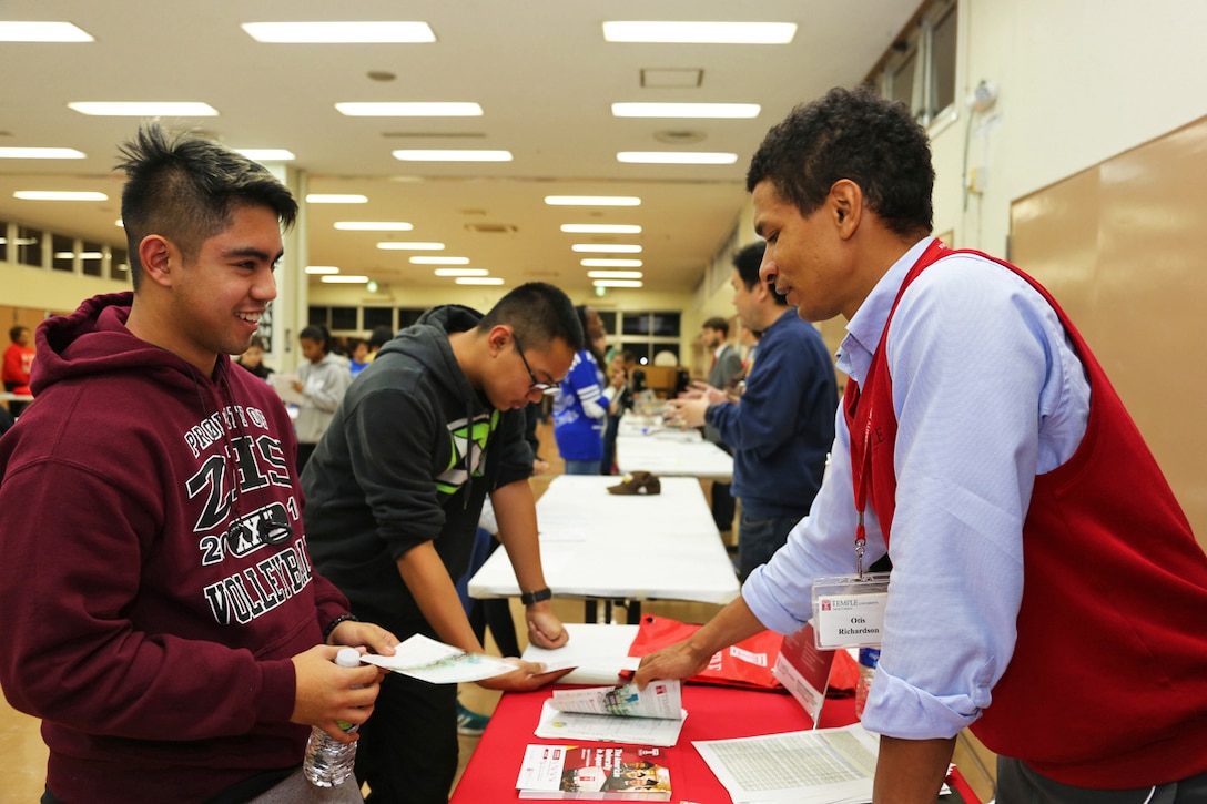 A student receives information from admission counselor Otis Richardson of Temple University's Japan campus, during a college fair at Camp Zama, Japan, Nov. 10, 2016. Army photo by Lance D. Davis