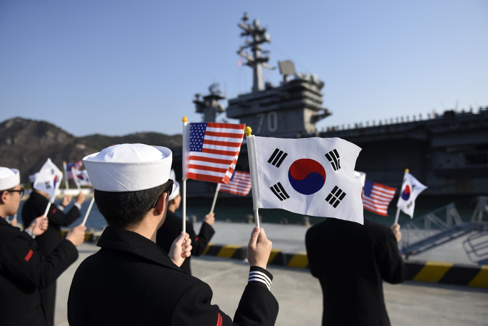 Republic of Korea (ROK) sailors wave flags as Nimitz-class aircraft carrier USS Carl Vinson (CVN-70) pulls into ROK Fleet headquarters, March 15. The Carl Vinson Carrier Strike Group is on a regularly scheduled Western Pacific deployment as part of the U.S. Pacific Fleet-led initiative to extend the command and control functions of U.S. 3rd Fleet. 