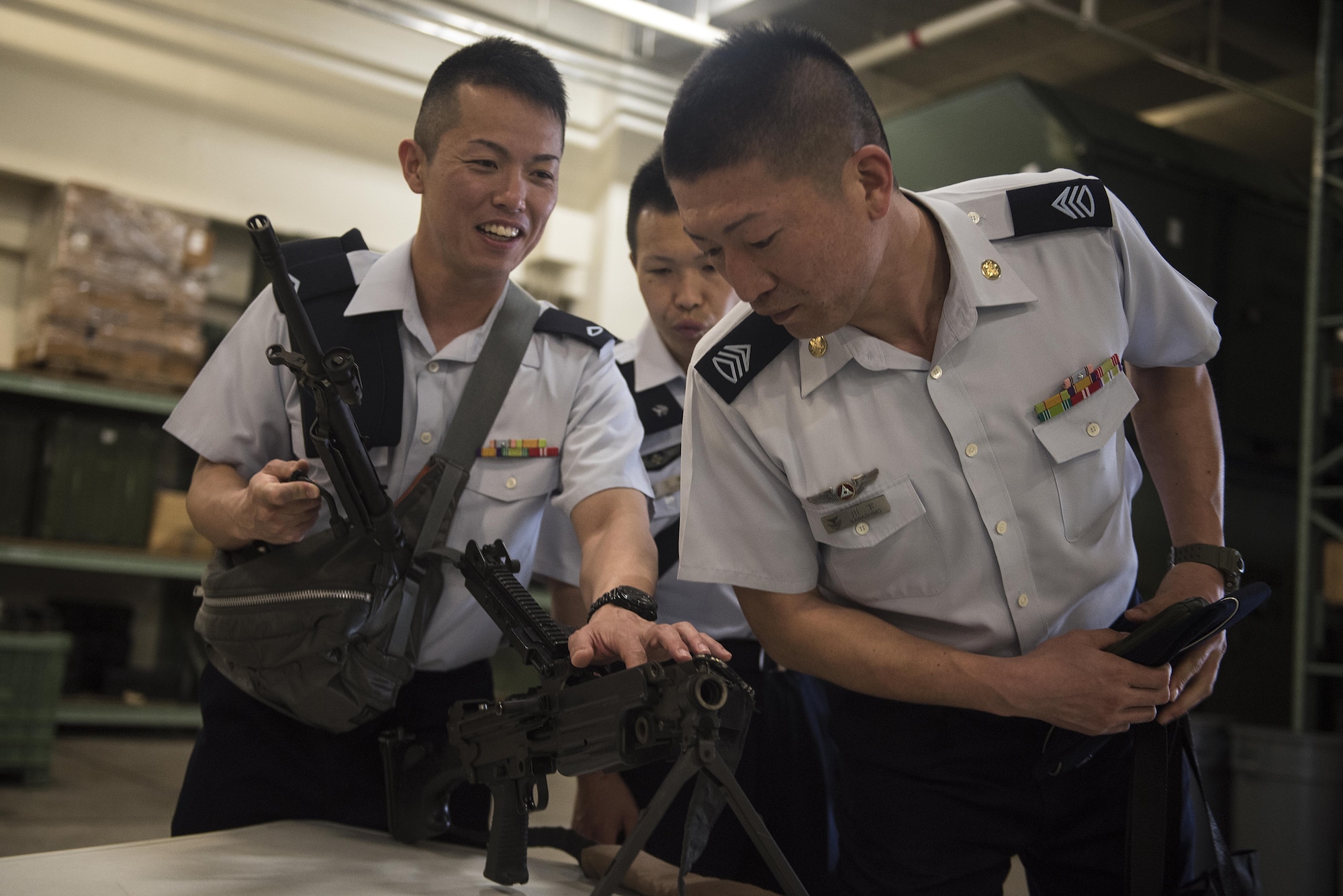 Members of the Japan Air Self-Defense Force learn about and handle different weapons during a tour of the Security Forces Squadron March. 14, 2017, at Kadena Air Base, Japan. The JASDF security forces members toured the SFS to get a first-hand look at U.S. security operations and training. (U.S. Air Force photo by Airman 1st Class Corey Pettis/Released)