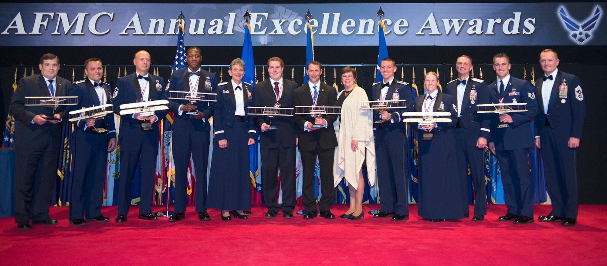 Air Force Material Command annual award winners are joined on stage by Gen. Ellen M. Pawlikowski, AFMC commander, Chief Master Sgt. Jason L. France, AFMC command chief, and Patricia M. Young, AFMC executive director, at the end of the command’s annual awards banquet March 8 in the National Museum of the Air Force at Wright-Patterson Air Force Base, Ohio. Among them are Brett Castle, an energy management technician for the 66th Air Base Group, won the Civilian Category I of the Year award; Brian Carr, Joint Surveillance Target Attack Radar System Recapitalization deputy Radar Integrated Product Team lead, captured the Civilian Category II of the Year award and Lt. Col. Timothy M. Helfrich, Communication Systems Quick Reaction Capability Branch materiel leader who manages the Battlefield Airborne Communications Node program, won the Field Grade Officer of the Year award. (U.S. Air Force photo by R.J. Oriez) 