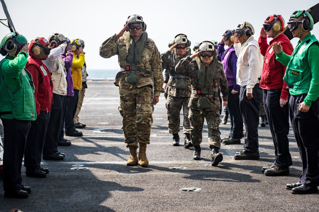 Crew members from the aircraft carrier USS Carl Vinson salute as Army Gen. Vincent K. Brooks, commander of  Combined Forces Command and U.S. Forces Korea arrives on the flight deck, March 12, 2017. Navy photo by Petty Officer 2nd Class Sean M. Castellano