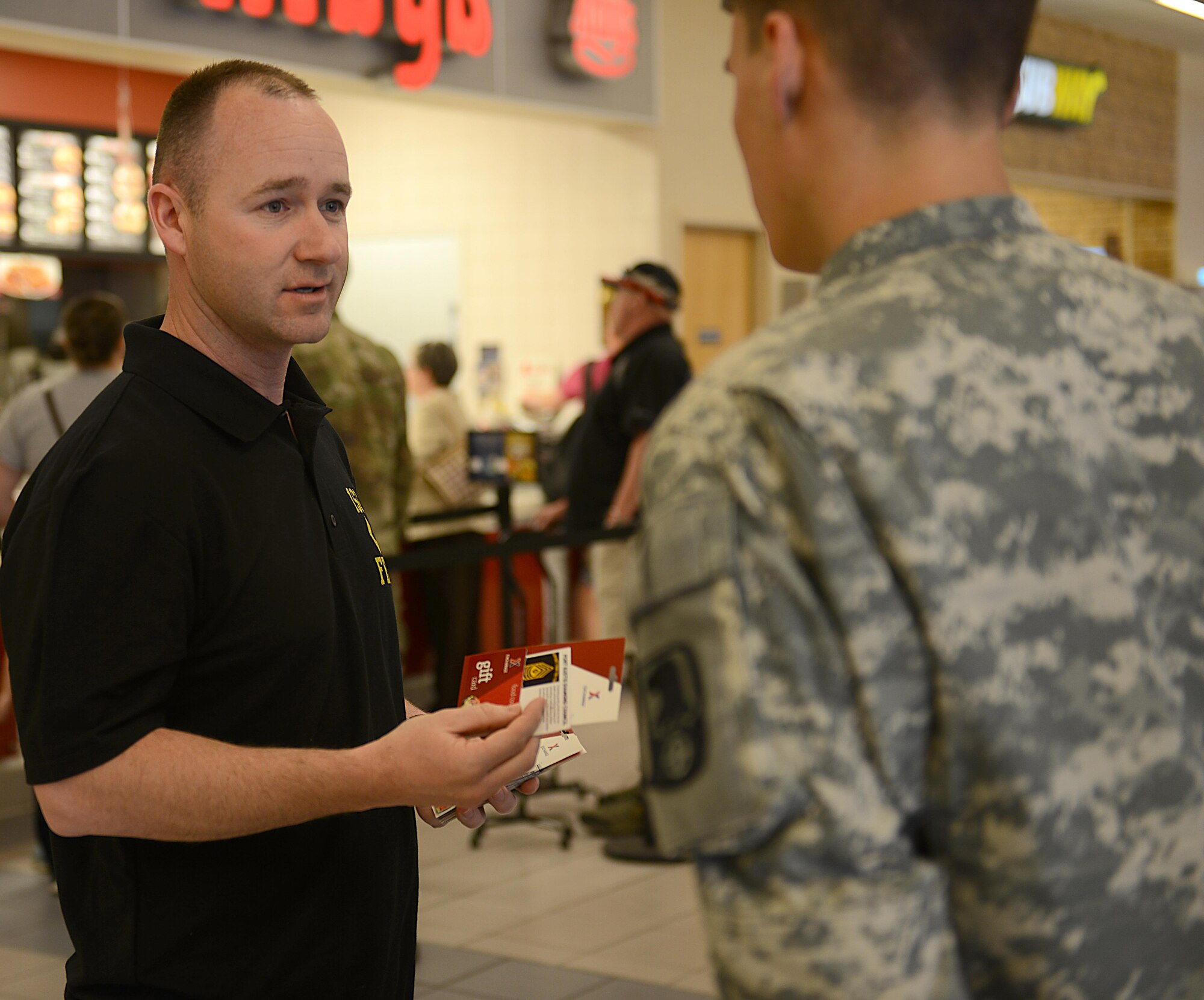 U.S. Army 1st Sgt. Ryan Reichard, Charlie Company, 222nd Aviation Regiment first sergeant and Fort Eustis Diamond Council treasurer, presents a gift card to a junior enlisted Soldier at Joint Base Langley-Eustis, Va., March 9, 2017. The Diamond Council distributed gift cards to junior enlisted service members to help pay for their lunch at the Exchange Food Court. (U.S. Air Force photo/Staff Sgt. Teresa J. Cleveland)