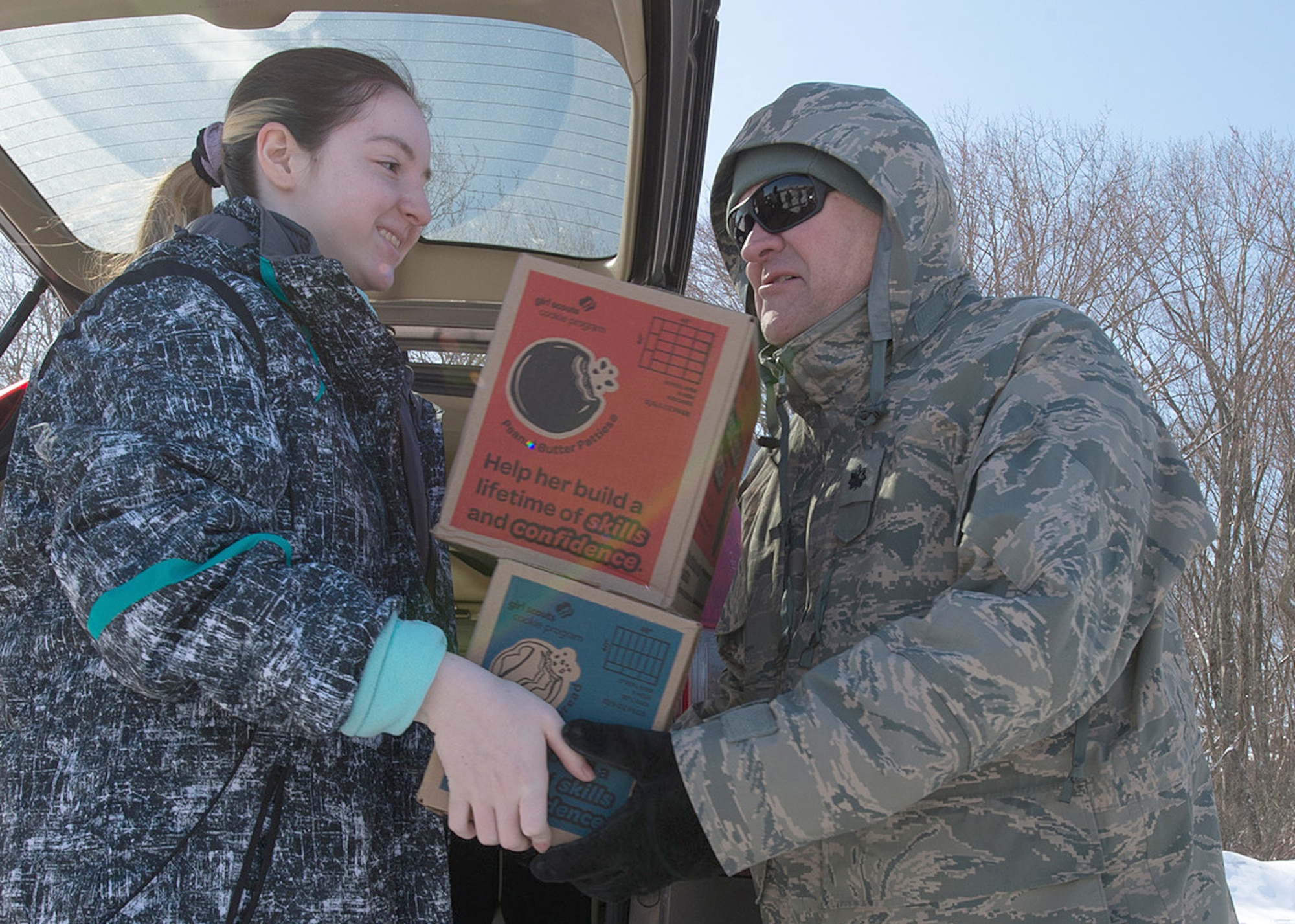 Lt. Col. Anthony J. Puleo, chief engineer for C3I and Networks Architecture and Engineering Branch, accepts cookies from Eliana Greenstein, a Girl Scout from Marlborough, Mass., during a Cookies for a Cause event on base March 11. During the event, Hanscom volunteers and the Girl Scouts of Eastern Massachusetts gathered to distribute approximately 18,000 boxes of Girl Scout cookies to military. (U.S. Air Force photo by Walter Santos)