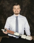 Picatinny Arsenal engineer, Michael Markowitch, holding a demonstration model of the Indirect Fire Munition (IDFM) Non-Lethal Cargo Carrier Mortar for which he and engineers Francesco Rizzi, Bryan Drake, Jason Surmanek, Samuel Perez, Raymond Trohanowsky, Wooje Na, and Piotr Czerechowski were granted US Patent No 9528802 B1. 