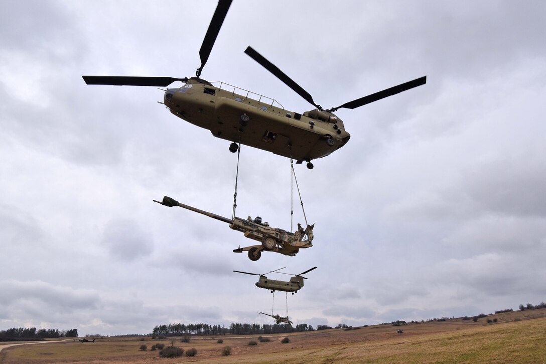 Two CH-47 Chinook helicopters liftoff with howitzers  during slingload operations during Dynamic Front II at the 7th Army Training Command's Grafenwoehr Training Area, Germany, March 9, 2017. Army photo by Gertrud Zach
