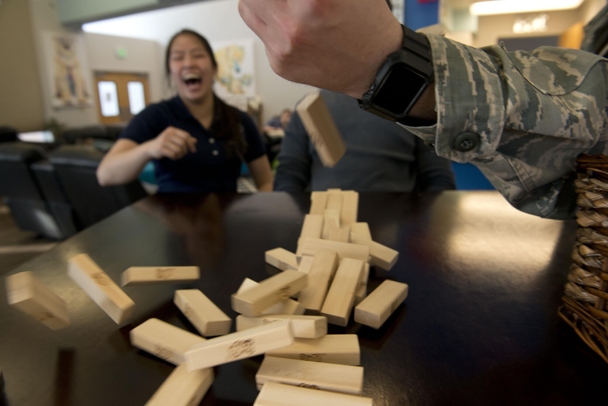 Air Force Staff Sgt. Janet Garrison, noncommissioned officer in charge of administration and logistics for the Professional Military Education Center laughs as Air Force Staff Sgt. Mike Smith, 673d Logistics Readiness Squadron material manager tries to stop a block tower from falling in the United Services Organization at Joint Base Elmendorf-Richardson, Alaska, March 10. The two noncommissioned officers were at the United Services Organization as part of a mentorship program held to open doors for Airmen talk in an off-duty environment.