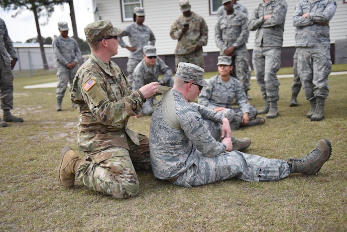 Army Sergeant Wesley Brantley, South Carolina Medical Detachment pre-mobilization assistance staff member, (left) applies a field dressing to Senior Airman Joseph C Kohnke, 628th Civil Engineer Squadron, engineer, (right) at McCrady Training Center March 8, 2017. Thirty Airmen from Joint Base Charleston attended the weeklong war skills training that taught land navigation, combat casualty care, improvised explosive device identification procedures, hand-to-hand combat skills and team building exercises.