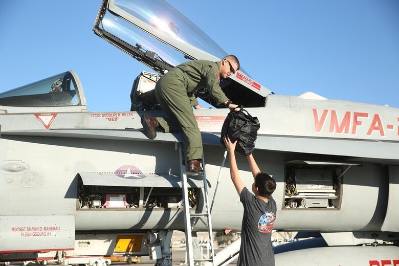 Lt. Col. Douglas Miller, commanding officer of Marine Fighter Attack Squadron (VMFA) 232 “Red Devils,” accepts personal luggage from his son before departing Marine Corps Air Station Miramar, Calif., March 11. Marine Fighter Attack Squadron (VMFA) 232 “Red Devils,” the oldest Marine fighter attack squadron, will spend six months training in the Asia-Pacific region and northern America.  (U.S. Marine Corps photo by Sgt. David Bickel/Released)