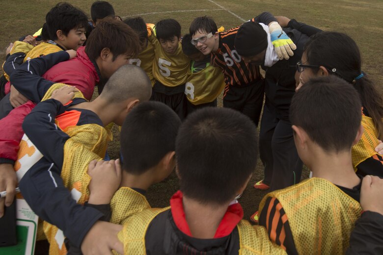 Yomitan Elementary School’s soccer team and Marine Corps Community Services’ soccer team, The Bandits, huddle on a soccer field with their coaches before the MCCS’ Friendship Soccer Game March 11 aboard Camp Foster, Okinawa, Japan. The players were divided into two teams; the teams were an even mix of the Yomitan team and MCCS’ team. This allowed both teams to experience playing alongside new players and against their teammates, teaching them the different styles of soccer other cultures have. 