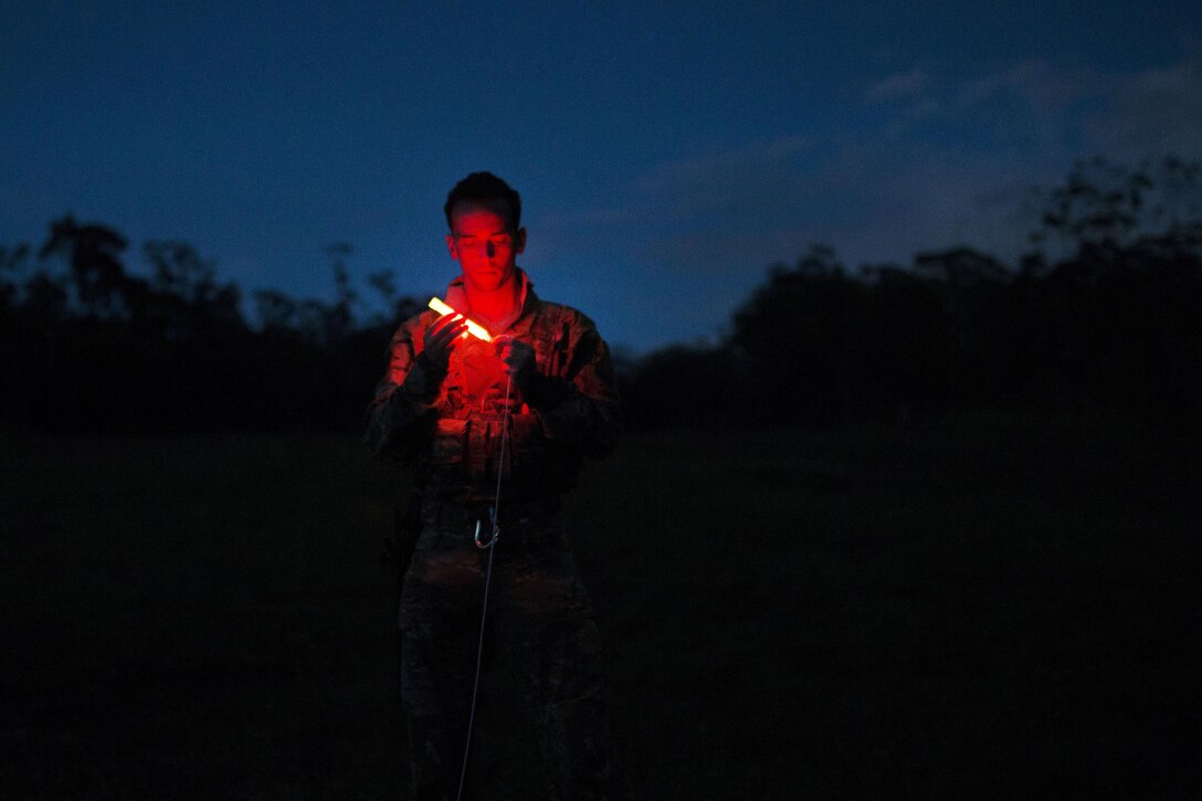 Air Force Senior Airman Jonathan Harvey ties a chemlight to 550-cord rope during a demonstration on how to contact friendly forces during survival training at the Army's Jungle Operations Training Course in Hawaii, March 8, 2017. Harvey is a survival, evasion, resistance and escape specialist assigned to the 106th Rescue Wing. Air National Guard photo by Staff Sgt. Christopher S. Muncy