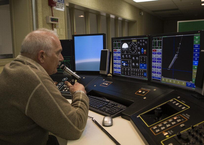 Glynn Breuer, 5th Operations Support Squadron contractor system operator, uses a microphone to communicate with instructors in the B-52H Stratofortress weapons system trainer during a simulated flight at Minot Air Force Base, N.D., March 8, 2017. Breuer maintains and operates the WST for base aircrews. (U.S. Air Force photo/Airman 1st Class Alyssa M. Akers)