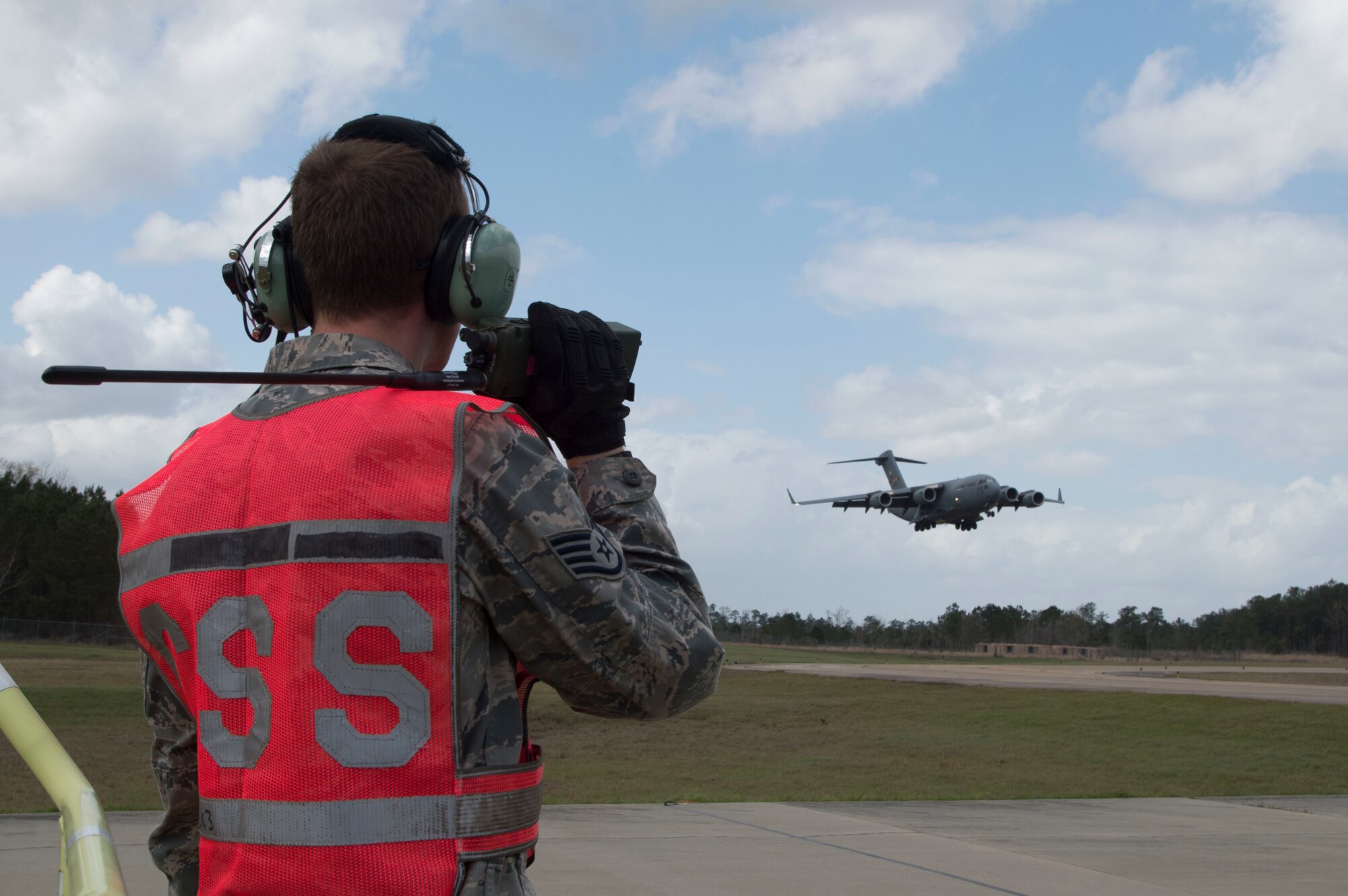 U.S. Air Force Staff Sgt. Benjamin Oehlke an aerial maintainer with the 621st Contingency Response Wing, monitors a U.S. Air Force C-17 Globemaster III as it performs landing maneuvers during exercise Crisis Response 2017, March 6, 2017, Camp Shelby, Miss. The 621st Contingency Response Wing is highly-specialized in training and rapidly deploying personnel to quickly open airfields and establish, expand, sustain, and coordinate air mobility operations. (U.S. Air Force photo by Staff Sgt. Robert Waggoner/RELEASED)