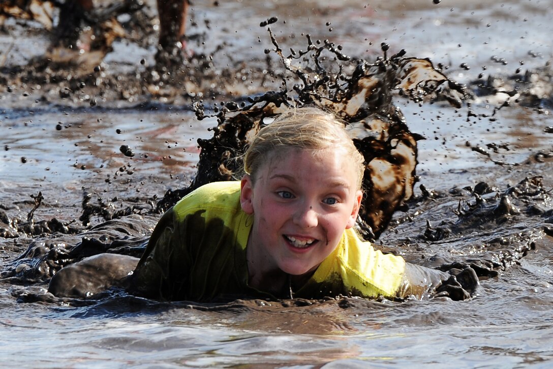 A military child crawls through mud