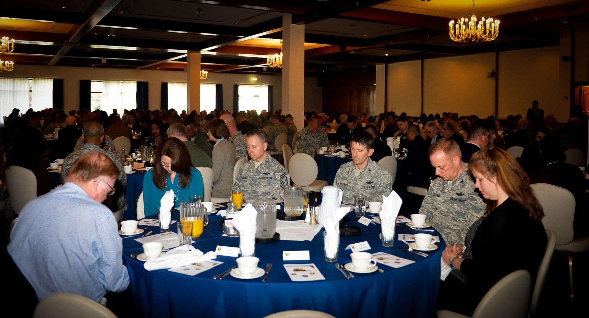 Military and civilian members of the Department of Defense bow their heads in prayer during a National Prayer Breakfast on Ramstein Air Base, Germany, March 13, 2017. The annual event is open to people of all religious backgrounds, and even to people of no religion. The 86th Airlift Wing Chaplain Corps hosted the prayer breakfast. (U.S. Air Force photo by Airman 1st Class Joshua Magbanua)